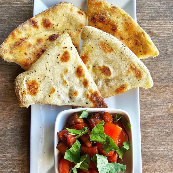 Four pieces of Artisan Wood Fired Kitchen's focaccia bread with a side of bruschetta.