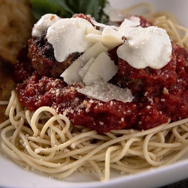 Spaghetti and meatballs with red sauce, fresh ricotta, and shaved Parmesan cheese.
